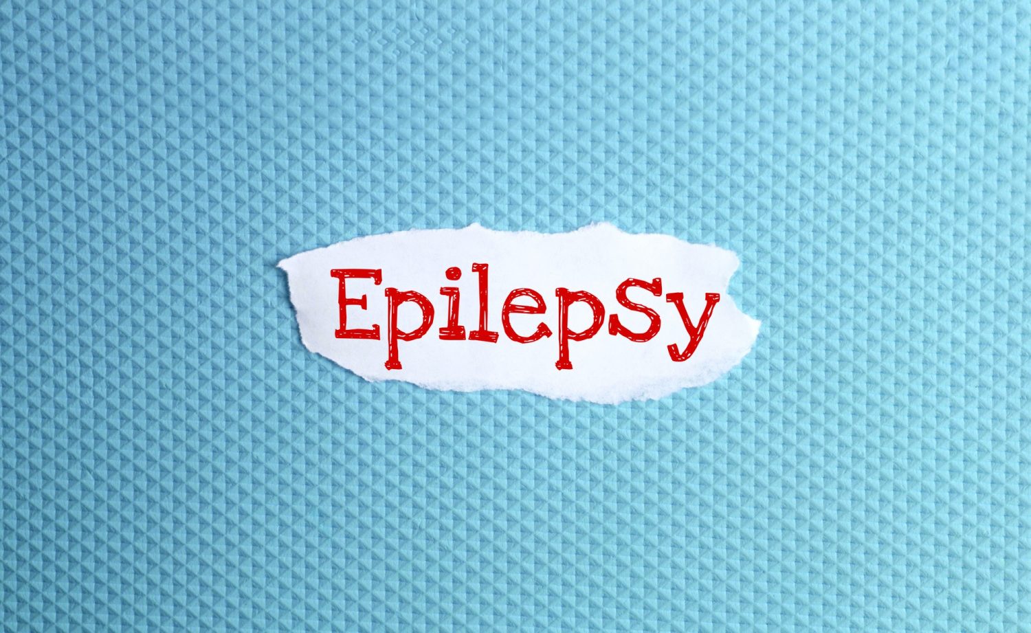 a torn paper written with inscription epilepsy on a blue background